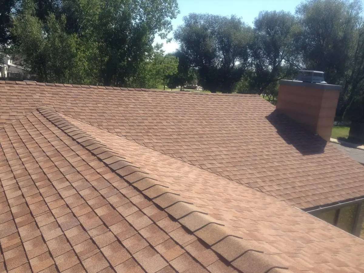 New tan shingle roof with hip lines and a brick chimney