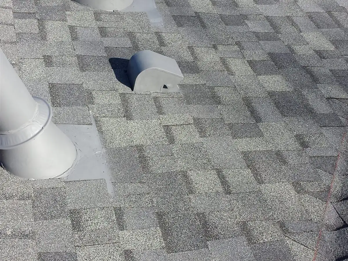 New roof with freshly flashed plumbing vent pipes and a roof vent